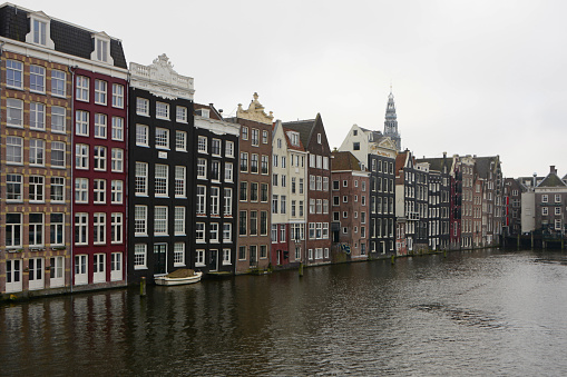 Amsterdam / Netherlands : Aerial view over a canal with the focus on the canal houses standing next to another. View with al lot of details. Residential area in the city center,  without people. In the background the old church tower.