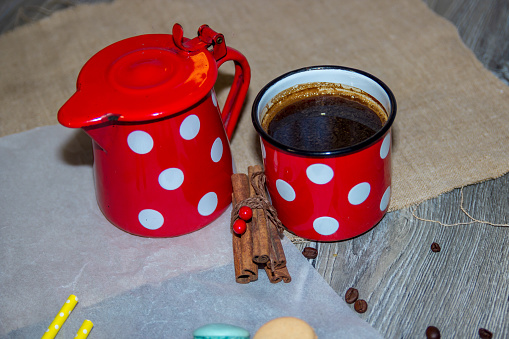 Black coffee in a white mug with cinnamon sticks on a saucer on a grey table