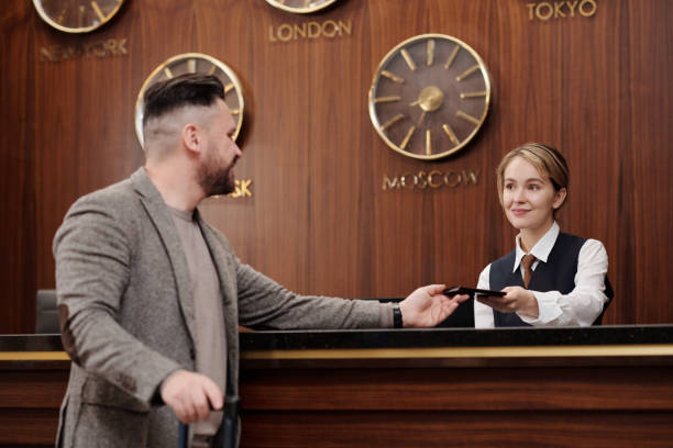 istock Young female receptionist looking at male client while passing him passport 1471856561