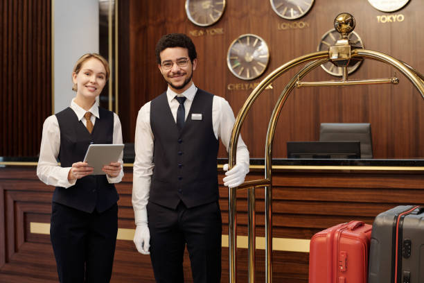 Two young elegant employees of luxurious hotel waiting for new guests stock photo