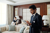 Young elegant entrepreneur in formalwear using tablet in hotel room
