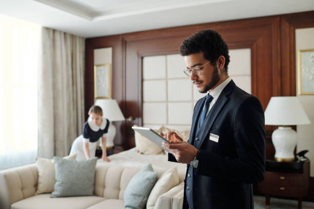 Young elegant entrepreneur in formalwear using tablet in hotel room stock photo