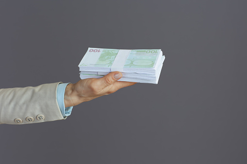 Closeup on business woman with euros money packs isolated on gray.