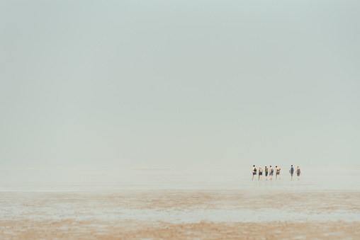 a group of people in the distance is walking through the Wadden Sea at low tide