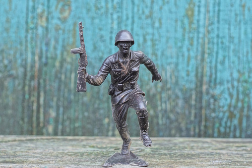 one big black old plastic soldier stands on a gray table against a green wall