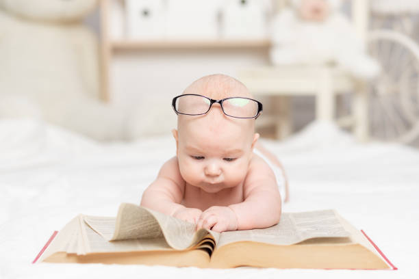 istock baby reading a book or looking at it in the nursery, learning and development concept 1471859939