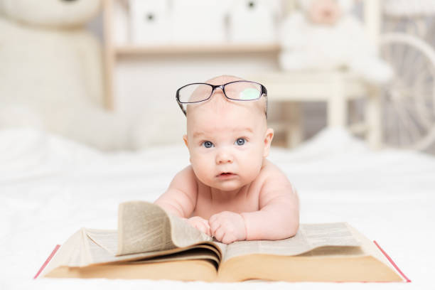 istock baby reading a book or looking at it in the nursery, learning and development concept 1471859940