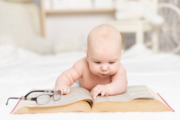 istock baby reading a book or looking at it in the nursery, learning and development concept 1471859941