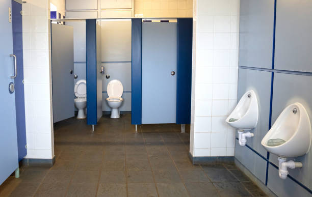 Stock photo shows Interior of public_toilets showing neatly arranged urinals in a gents mens wc bathroom restroom washroom. The space is clean, well-lit, and functional, emphasizing hygiene, privacy, and practical urban facility design