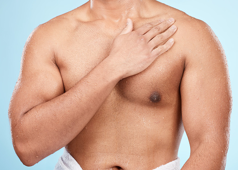 Skin, body and man after skincare shower or bath for hygiene and wellness isolated against a blue background. Topless, clean and muscles of fit male doing self care cosmetic routine