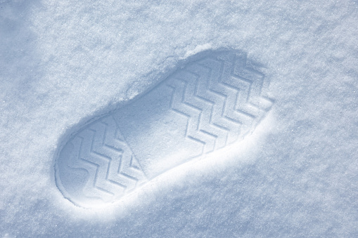 Boot imprint in a snowdrift on a sunny summer day, close-up top view