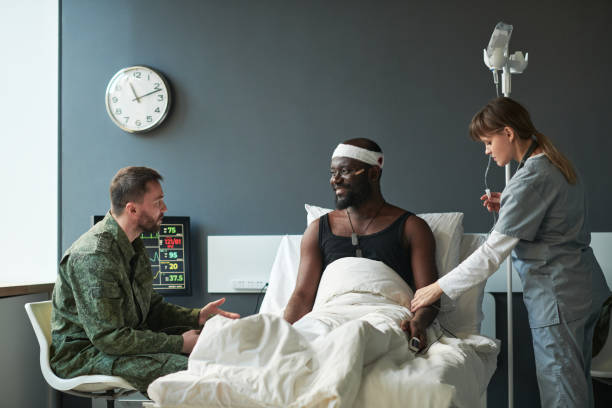 un jeune soldat en uniforme militaire parle à son ami blessé - doctor medical occupation healthcare and medicine group of people photos et images de collection