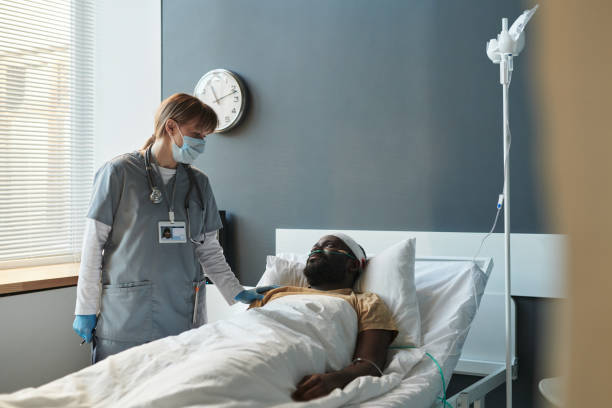 istock Young caregiver in protective mask communicating with injured patient 1471865925
