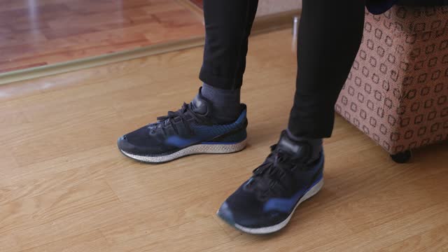 Young man puts on sports shoes for jogging.