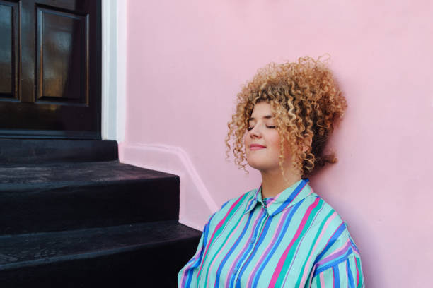 Young woman with Afro hair sitting on front steps, clearing her mind.