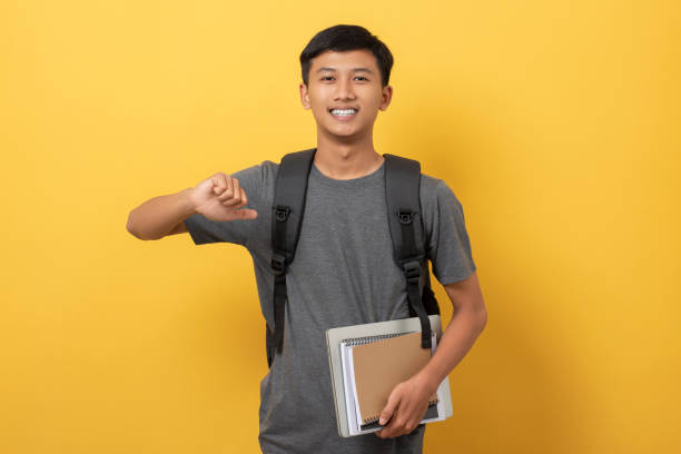 istock Young college student with books and backpack isolated on yellow background 1471870845