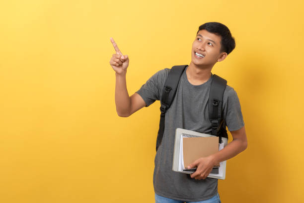 istock Young college student with books and backpack isolated on yellow background 1471872066