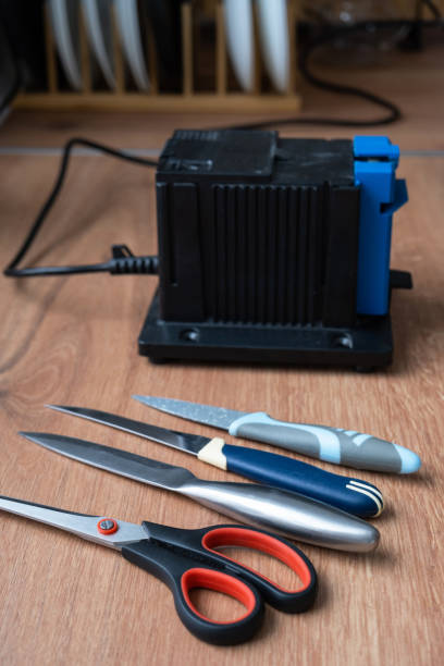 istock Sharpening a knife on an electric sharpener at home. Flatlay knife blade, scissors, sharpeners, dust flies on the machine. 1471879568