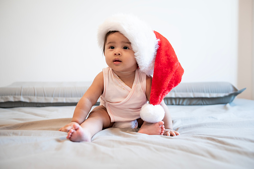 A Baby girl laughing wearing santa claus hat at home