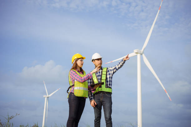 equipo de ingenieros asiáticos discutiendo y verificando el progreso del campo de las turbinas eólicas. - alternative energy electricity wind turbine team fotografías e imágenes de stock