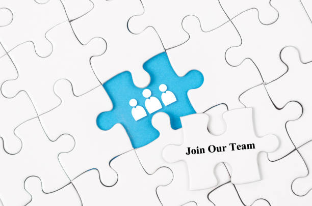 The Join our team concept. White jigsaw puzzle with word and blue background stock photo