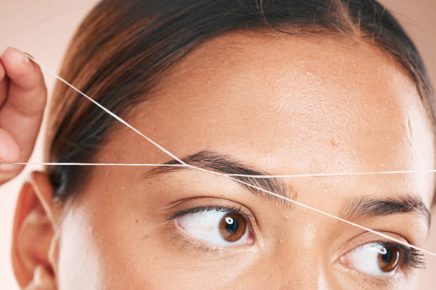 istock Threading, eyebrows and beauty with a model black woman in studio on a beige background for hair removal. Eyes, zoom and wellness with an attractive young female using a product on her face 1471885346
