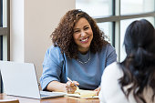 Mature businesswoman smiles encouragingly at unrecognizable female job applicant