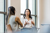 Young adult woman gestures and talks during interview with businesswoman