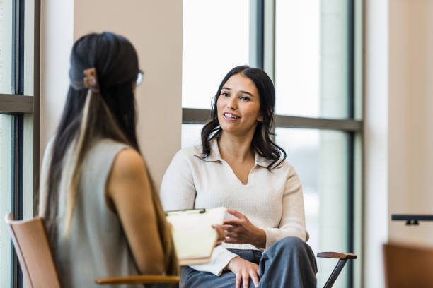 Unrecognizable manager takes notes during interview with young adult woman stock photo