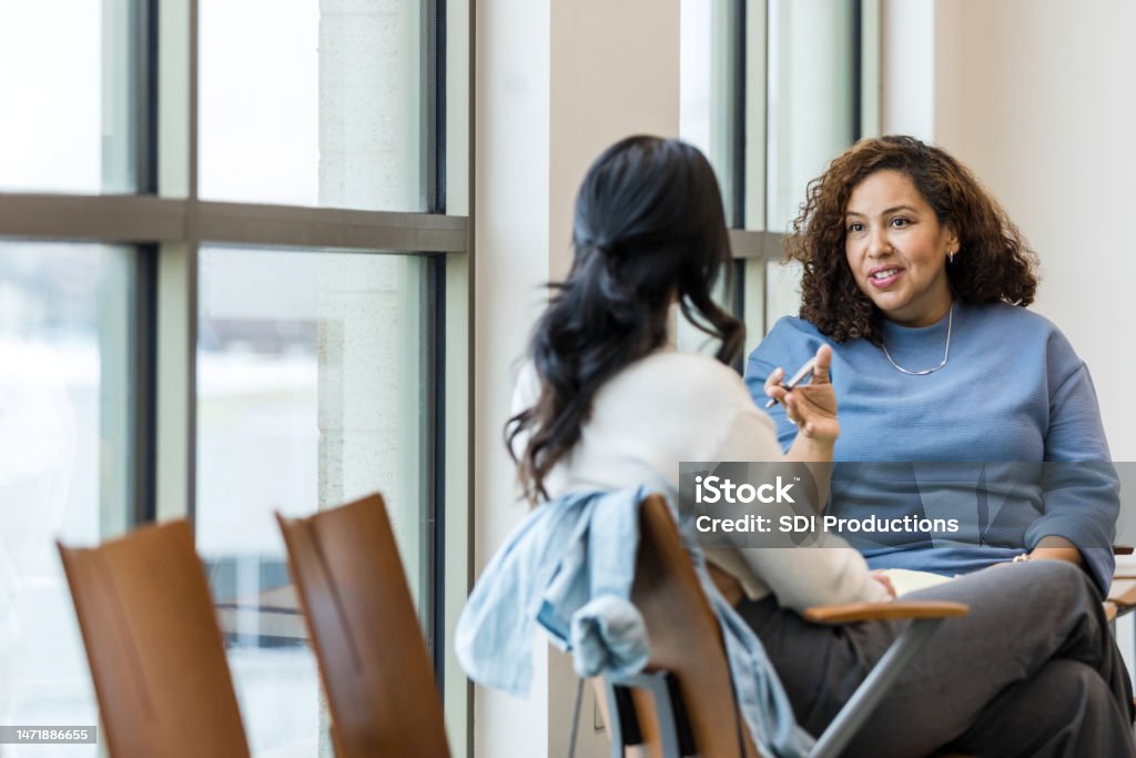 Unrecognizable female client listens as female counselor gives advice An unrecognizable patient listens as her mature adult female therapist gives her some straightforward advice. Mental Health Stock Photo