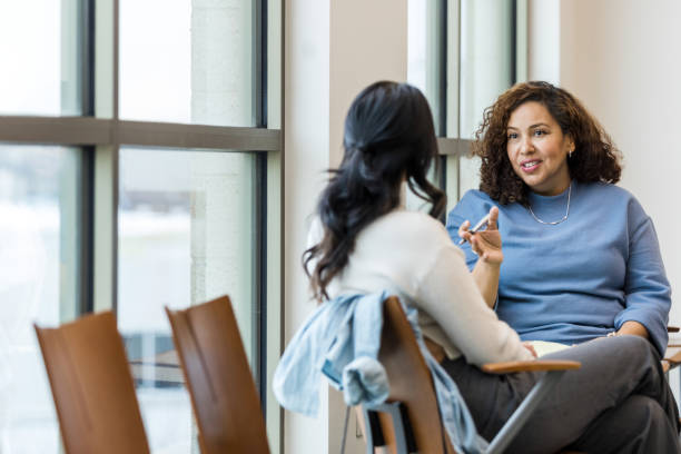 Unrecognizable female client listens as female counselor gives advice stock photo