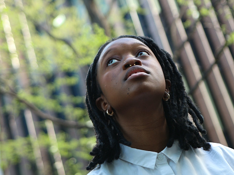 Portrait of Young Black Woman looking up in outdoors.
Canadian aspirational and satisfaction.