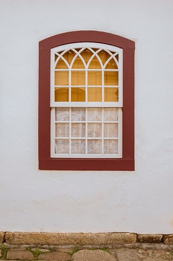 Paraty, Brazil. Colorful window with lace curtain of old colonial period house in historic downtown.