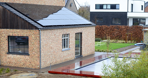 Leuven, Vlaams-Brabant, Belgium-  March 7, 2023: on a rainy day every wet surface of wood, in this case African Padauk wood plank floor terrace around a private outdoor swimming pool looks like a freshly laid varnished one.