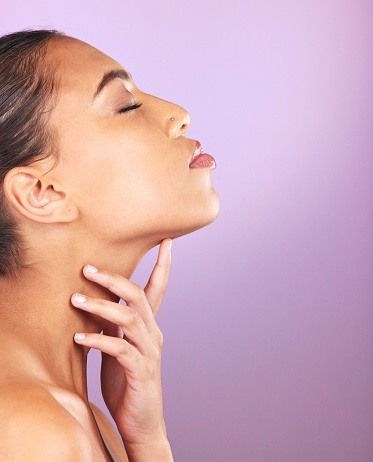 Beauty, skincare and mockup with a model black woman touching her face in studio on a purple background. Wellness, luxury and cosmetics with an attractive young female posing to promote a product