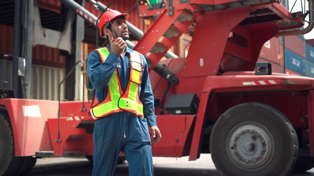 Foreman use walkie talkie to communicate and control staff in container area. stock photo