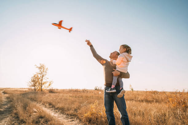 istock Happy Father And Child Having Fun Playing Outdoors. Smiling Young Dad And Daughter Spending Time Together, let an airplane into the sky 1471896165