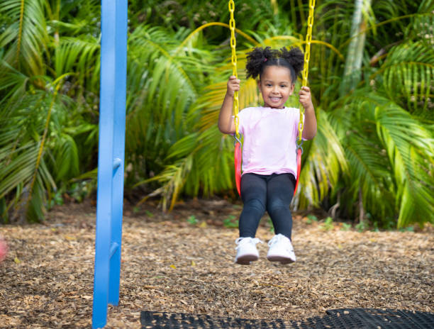 istock Cute Little girl using a swing on a daycare playground 1471897522