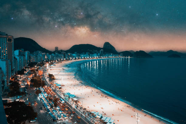 panoramic aerial view at night to Copacabana beach and buildings in Rio de Janeiro under the stars and Milky Way in the background stock photo