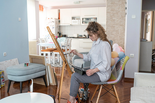 Creative beautiful woman painting at home
