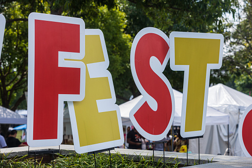 Large letters spelling FEST are planted in ground at fall festival.