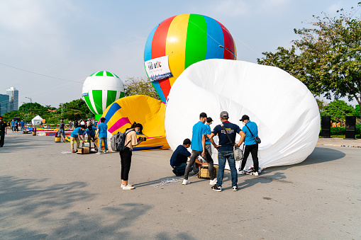 HOCHIMINH CITY, VIETNAM - JANUARY 22, 2022: Afternoon at the hot air balloon festival celebrating the founding of Thu Duc city above Thu Thiem tunnel. Technicians are inflating hot air balloons