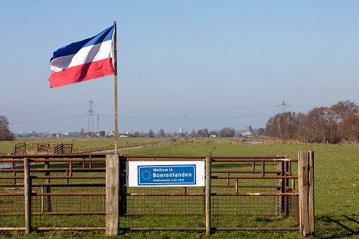 Rotterdam, The Netherlands -  March 2nd, 2023: Dutch flag upside down because of farmer protest in the Netherlands and a sign that this farmland is independent of the European Union