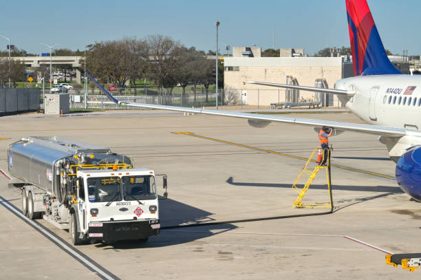 Fuel tanker parked alongside a Delta Air Lines passenger jet at Austin airport in Texas for refuelling Austin, Texas - February 2023: Delta Air Lines Airbus A220 passenger jet (registration N144DU) being refuelled  at rthe city's airport. austin airport stock pictures, royalty-free photos & images