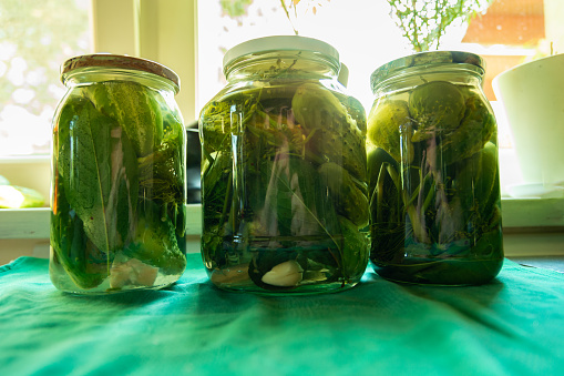 Close-up of canned fresh homemade green cucumbers in glass jars