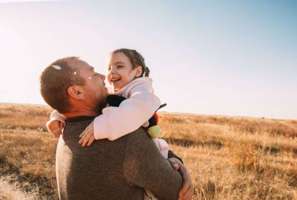 Happy Father And Child Having Fun Playing Outdoors. Smiling Young Dad And Daughter Spending Time Together In Nature. Parent And His Kid Relaxing In Park.