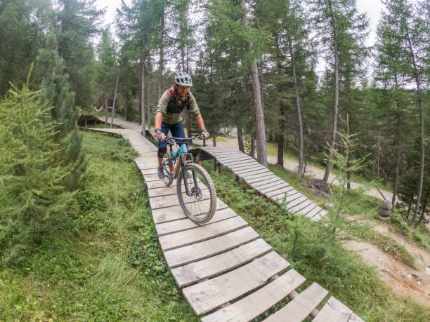 istock Mountain biker riding down elevated wooden ramp in the pine forest 1471903154