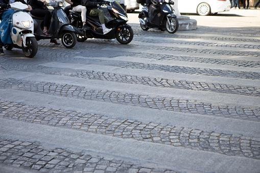 Motor scooters in a line waiting at a zebra crossing on Avenue des Champs-Elysees, Paris