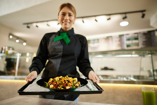 Pretty barmaid holding plate of salad