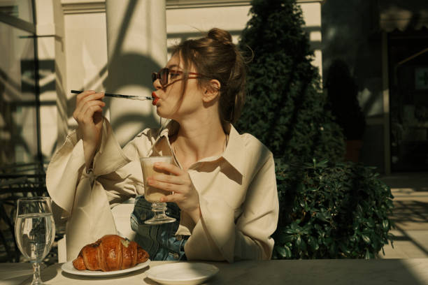 istock A girl in an open cafe eats coffee foam from a straw 1471905065